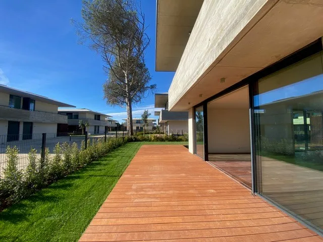 Contemporary villa in Quinta da Marinha with glass windows, wooden deck, and landscaped garden.